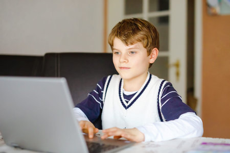 Little kid boy making school homework on computer notebook. Happy healthy child searching...