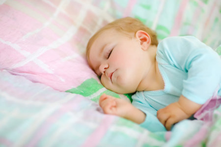 Adorable little baby girl sleeping in bed. Calm peaceful child dreaming during day sleep. Beautiful...