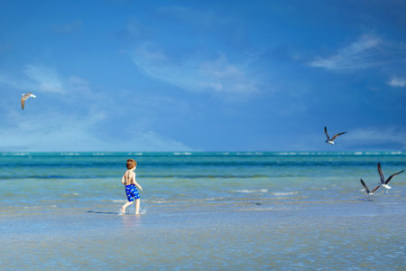 Active little kid boy having fun on Miami beach, Key Biscayne. Happy cute child running near ocean...
