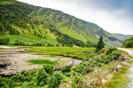 Idyllic view in Glendalough Valley, County Wicklow, Ireland. Mountains, lake and tourists walking pathsの写真素材