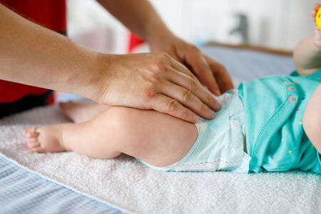 Close-up of father changing diaper of his newborn baby daughter. Little child, girl on changing table in bathroom with rattle toysの写真素材