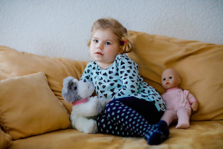 Cute little toddler girl in nightwear pajamas watching cartoons or movie on tv. Happy healthy baby...