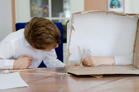 Two little school kids boy making paper doll theatre. Happy children and friends creating figures...