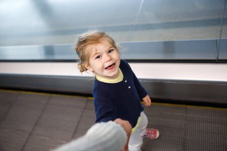 Adorable little toddler girl at the airport. Lovely child walking to the gate and going on family vacations by plane. Positive happy child.の写真素材