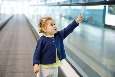 Adorable little toddler girl at the airport. Lovely child walking to the gate and going on family...