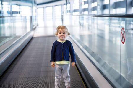 Adorable little toddler girl at the airport. Lovely child walking to the gate and going on family vacations by plane. Positive happy child.の写真素材