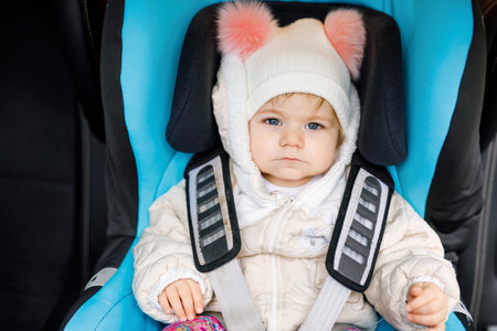 Adorable baby girl with blue eyes sitting in car seat. Toddler child in winter clothes going on family vacations and jorney. Safe travel, children safety, transportation conceptの写真素材
