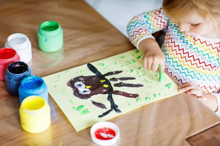 Closeup of little creative toddler girl painting with finger colors an owl bird. Child having fun with drawing at home, in kindergaten or preschool. Games, education and distance learning for kids.の写真素材