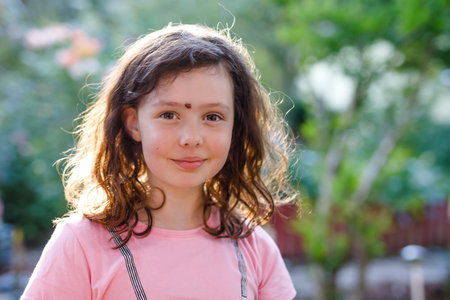 Portrait of little school girl with ladybug on face. Happy smiling excited child on warm summer...