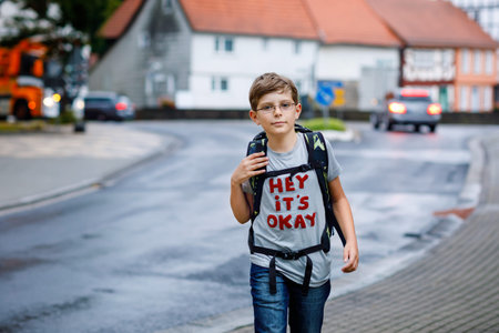 Happy little kid boy with glasses and backpack or satchel. Schoolkid on the way to middle or high...