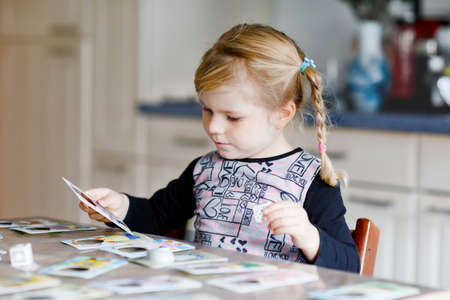 Adorable cute toddler girl playing picture card game. Happy healthy child training memory, thinking. Creative indoors leisure and education of kid during pandemic coronavirus covid quarantine diseaseの写真素材