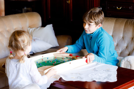 Toddler girl and kid boy playing table soccer with family at home. Smiling children, siblings play...