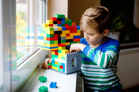 Little kid boy playing with lots of colorful plastic blocks. Adorable school child having fun with...