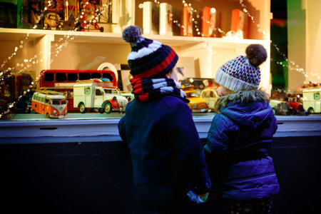 Two little toddlers, boy and girl looking on car toys in a window on Christmas time season....