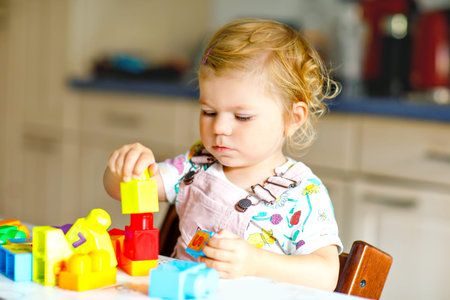 Adorable toddler girl playing with educational toys in nursery. Happy healthy child having fun with...