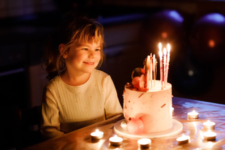 Adorable little toddler girl celebrating fourth birthday. Cute toddler child with homemade princess cake, indoor. Happy healthy toddler blowing 4 candles on cakeの写真素材