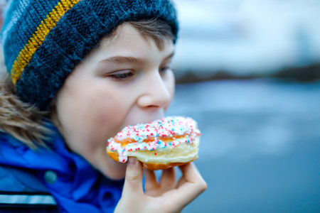 Kid boy eating sweet pie called Kreppel in German or rugelach sufganiyot. Child with cake, religious...