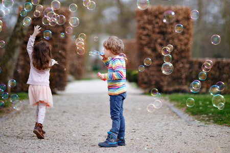 Preschool kid boy and little girl blowing on a dandelion flowers in park in the summer. Happy...
