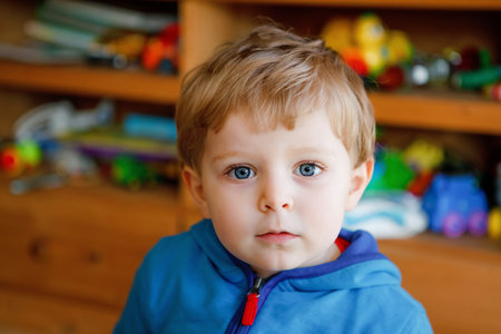 Portrait of little child, cute adorable toddler boy looking at the camera. Happy, curious kid at home, indoors.の写真素材