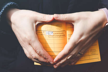Closeup of hand of woman holding German inernational certificate of the vaccination. Adult showing the information about her vaccine against covid 19 corona virus.の写真素材