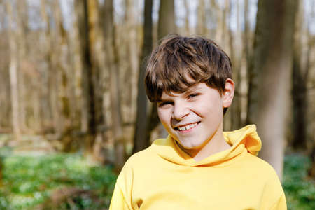 Portrait of elementary school kid boy. Happy smiling child looking at the camera. Boy in spring forest, making family outdoor adventure walk with family.の写真素材