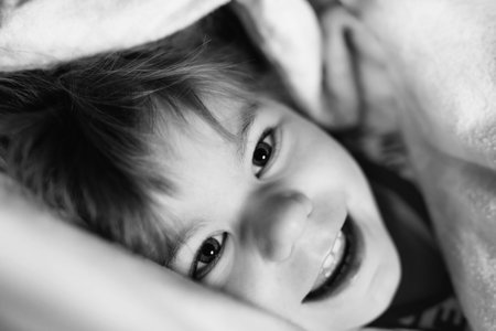 Little toddler girl having fun in bed after wake up. Healthy child jump and play hide and seek with...