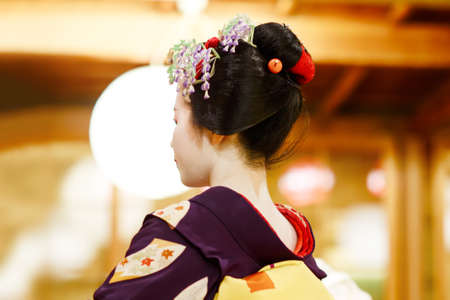Maiko apprentice showing Japanese traditional dance. Maiko is an apprentice geisha. Maikos performing songs, playing shamisen or instruments for visitors on ozashiki.の写真素材