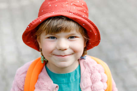 Portrait little preschool girl going to playschool. Healthy toddler child walking to nursery school and kindergarten. Happy child with backpack on the city street, outdoors.の写真素材