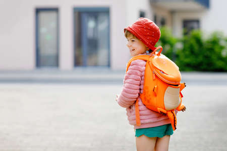 Cute little preschool girl going to playschool. Healthy toddler child walking to nursery school and kindergarten. Happy child with backpack on the city street, outdoors.の写真素材