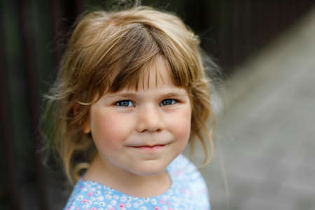 Portrait of happy smiling toddler girl outdoors. Little child with blond hairs looking and smiling at the camera. Happy healthy child enjoy outdoor activity and playing.の写真素材