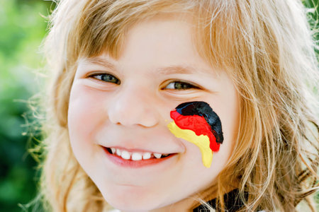 Little blond preschool girl watching soccer football cup game on public viewing. Happy joyful...