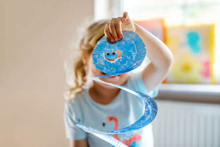 Little preschool girl painting with finger colors making animal snake craft at home or nursery. Indoor activity with happy creative toddler child, homeschooling with parentsの写真素材