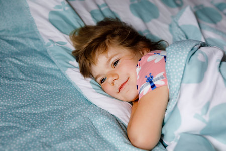 Cute little preschool girl sleeping in bed. Adorable baby child dreaming, healthy sleep of children...