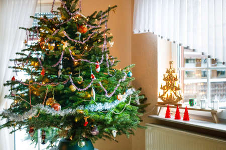 Decorated Christmas tree, indoors. Xmas tree decorations, vintage and modern. With lights illuminationの写真素材