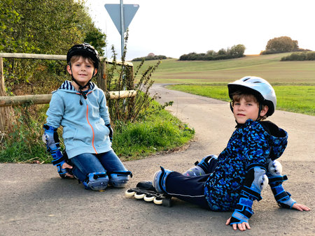 Two little kids boys skating with rollers in the city. Happy children, siblings and best friends in...