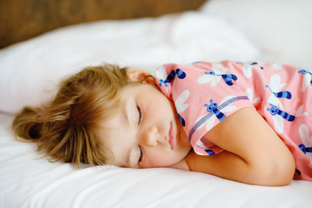 Cute little toddler girl sleeping in bed. Adorable baby child dreaming, healthy sleep of children by...