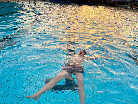School kid boy splashing in an outdoor swimming pool on warm summer day. Happy healthy preteen child...