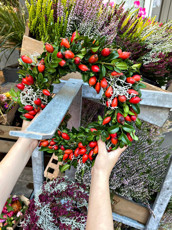 Little girl buy autumn door wreath at decor shop. Cute happy child play with autumnal decoration....