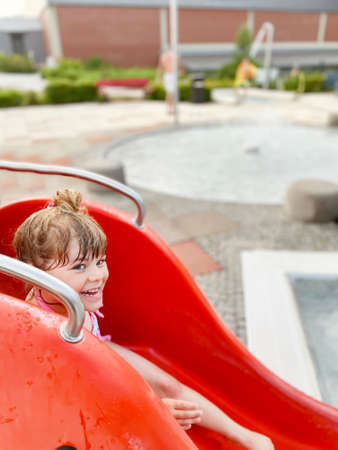 Little preschool girl splashing in an outdoor swimming pool on warm summer day. Happy healthy toddler child enjoying sunny weather in city public pool. Kids activity outdoors with water.の写真素材