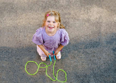 Little preschool girl jump and train with skipping rope. View from above on cute happy active child. Summer sports and activity for physical and mentally fitness of children.の写真素材