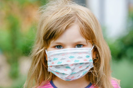 Little toddler girl on her first day on way to playschool with medical mask against corona covid...