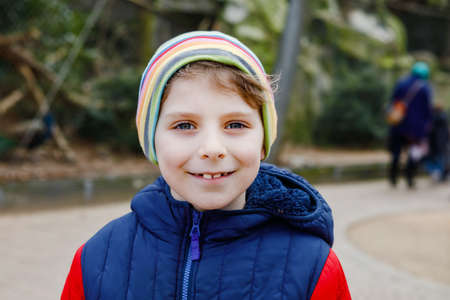Outdoor portrait of little kid boy in spring or autumn colorful clothes. Happy boy having fun in a zoo. Smiling childの写真素材