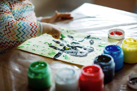 Closeup of little creative toddler girl painting with finger colors an owl bird. Child having fun with drawing at home, in kindergaten or preschool. Games, education and distance learning for kids.の写真素材