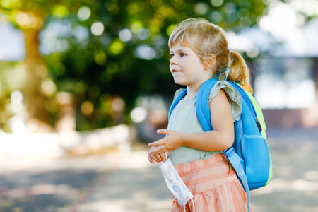 Little toddler girl on her first day on way to playschool with medical mask against corona covid...