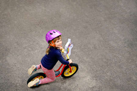 Little toddler girl running with balance bike on summer day. Happy child driving, biking with bicycle, outdoor activity. Happiness, childhoodの写真素材
