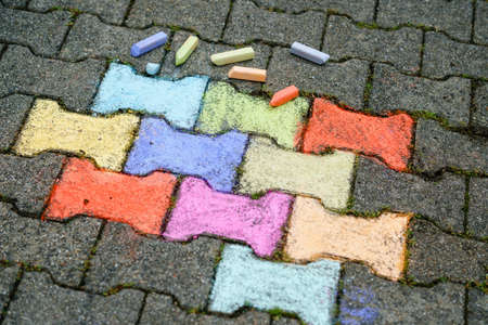 Figures painting with colorful chalks on ground on backyard. Children activity, drawing and creating pictures. Creative outdoors activity in summer.の写真素材