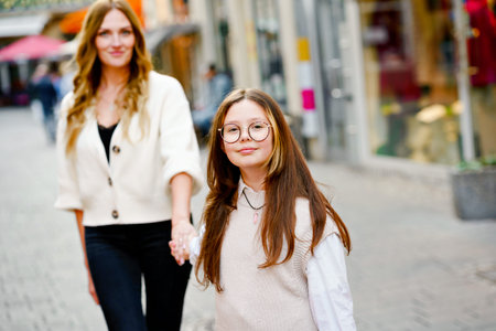 Young mother and school preteen girl making walk in the city. Happy family, woman and daughter with...