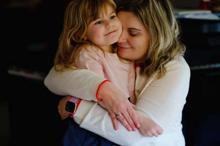 Happy young mother having fun cute preschool daughter, family portrait together. Woman with little girl indoors, at home. Mum with child hugging. Love, bonding.の写真素材