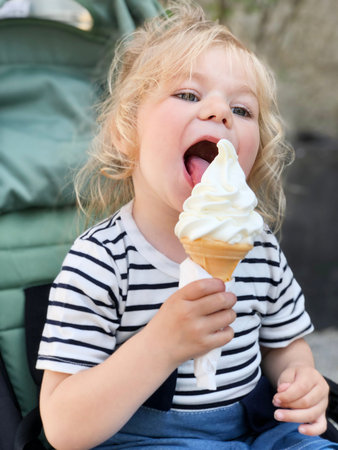 Cute funny preschool girl eating fruit ice cream. Happy healthy toddler child smiling and tasting...