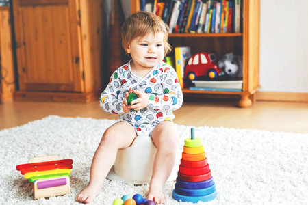 Closeup of cute little 12 months old toddler baby girl child sitting on potty.の写真素材
